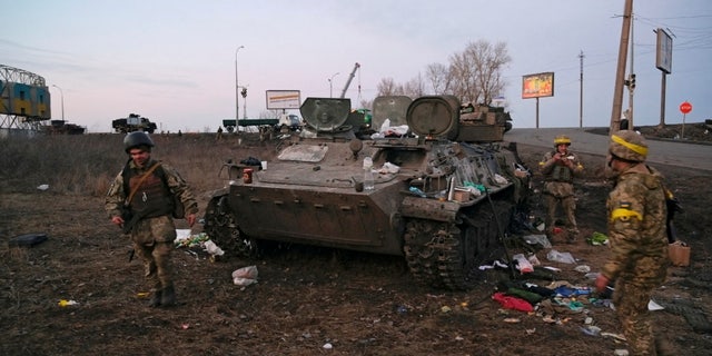 Ukrainian servicemen are seen next to a destroyed armored vehicle, which they said belongs to the Russian army, outside Kharkiv, Ukraine February 24, 2022.