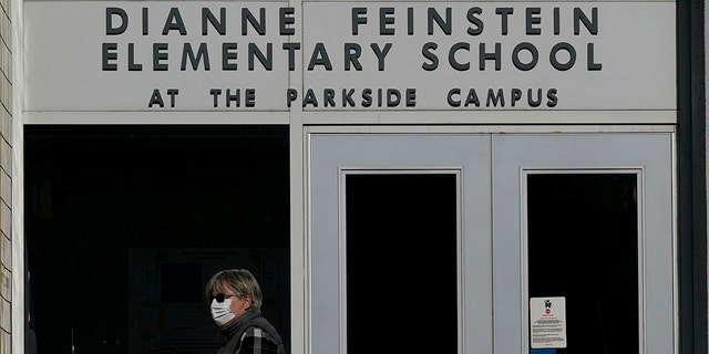 ARCHIVO - Un peatón camina debajo de un letrero de la Escuela Primaria Dianne Feinstein en San Francisco el 17 de diciembre de 2020. En una ciudad con el porcentaje más bajo de niños de todas las principales ciudades estadounidenses, las elecciones de la junta escolar en San Francisco a menudo han sido una ocurrencia tardía.  (Foto AP/Jeff Chiu, archivo)