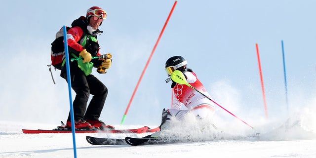 Eva Vukadinova of Team Bulgaria skis her run while a course worker is still repairing a broken gate during the Women's Slalom Run 1 on day five of the Beijing 2022 Winter Olympic Games at National Alpine Ski Centre on February 09, 2022 in Yanqing, China. 