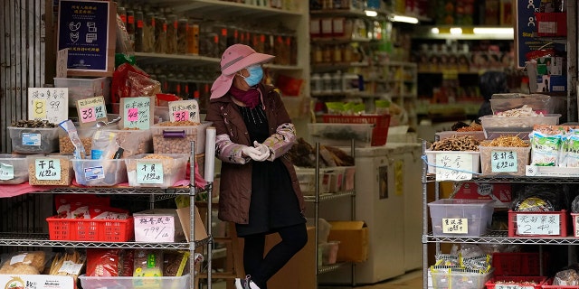 A woman stands at the entrance of a market in Chinatown in San Francisco, Sunday, Dec. 13, 2020. (Associated Press)
