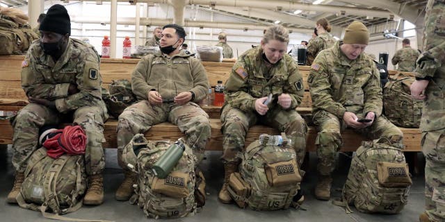 U.S. Army soldiers with the 18th Airborne Corps. sit with their gear as they wait to board a plane for deployment to Europe Thursday, Feb. 3, 2022 from Fort Bragg, N.C.