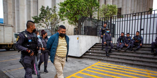 David Coronado Perez, who is alleged to be part of a human trafficking network, is being picked up by an officer in Guatemala City after his court hearing on Friday, February 4, 2022.  (AP Photo / Oliver de Ross)