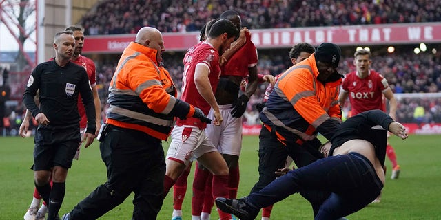 Stewards block a man attacking the pitch during an English FA Cup fourth round football match between Nottingham Forest and Leicester City at City Ground, Nottingham, England, Sunday, February 6, 2022. 