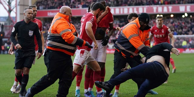 Stewards block a man attacking the pitch during an English FA Cup fourth round football match between Nottingham Forest and Leicester City at City Ground, Nottingham, England, Sunday, February 6, 2022. 