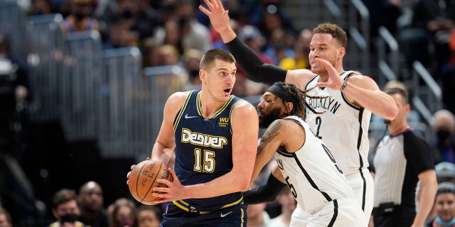 Denver Nuggets center Nikola Jokic, sinistra, looks to pass the ball as Brooklyn Nets guard DeAndre' Bembry, centro, and forward Blake Griffin defend in the first half of an NBA basketball game Sunday, Feb. 6, 2022, a Denver.