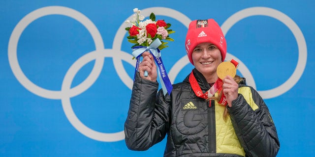 Natalie Geisenberger, of Germany, shows the gold medal at the podium for the luge women's singles at the 2022 Winter Olympics, Tuesday, Feb. 8, 2022, in the Yanqing district of Beijing. 