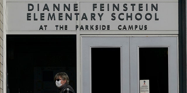 A pedestrian walks below a sign for Dianne Feinstein Elementary School in San Francisco Dec. 17, 2020. 