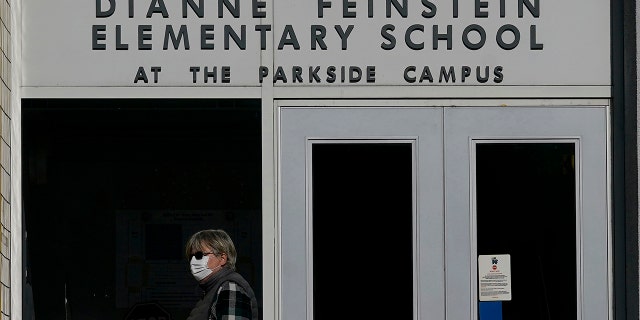 A pedestrian walks below a sign for Dianne Feinstein Elementary School in San Francisco on Dec.  17, 2020. The city's school board sought to rename 44 public schools they said honored public figures linked to racism, sexism and injustice. 