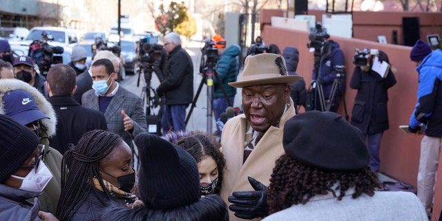 Attorney Ben Crump, center, speaks to residents of a building that had a fatal fire last month in the Bronx borough of New York, Tuesday, Feb. 8, 2022. (AP Photo/Seth Wenig)