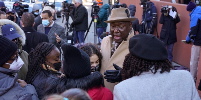 Attorney Ben Crump, center, speaks to residents of a building that had a fatal fire last month in the Bronx borough of New York, Tuesday, Feb. 8, 2022. (AP Photo/Seth Wenig)