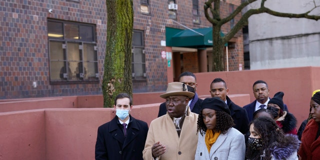 Surrounded by victims of a building fire and their families, attorney Ben Crump, second from left, speaks to reporters at a news conference in the Bronx borough of New York, Tuesday, Feb. 8, 2022. (AP Photo/Seth Wenig)