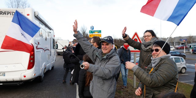 People wave to a convoy departing for Paris, Friday, Feb.11, 2022 in Strasbourg, eastern France. Authorities in France and Belgium have banned road blockades threatened by groups organizing online against COVID-19 restrictions. The events are in part inspired by protesters in Canada.