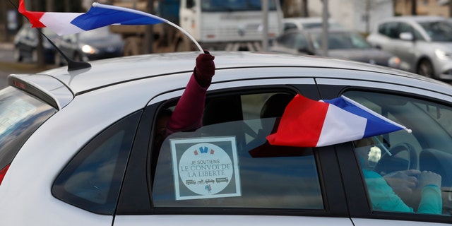 Protesters wave French flags from a car in a convoy departing for Paris, Friday, Feb.11, 2022 in Strasbourg, eastern France.