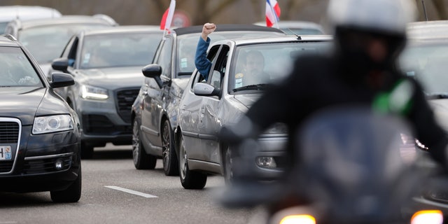 A protester clenches his fist from his car part of a convoy heading to Paris, Friday, Feb.11, 2022 in Strasbourg, eastern France.