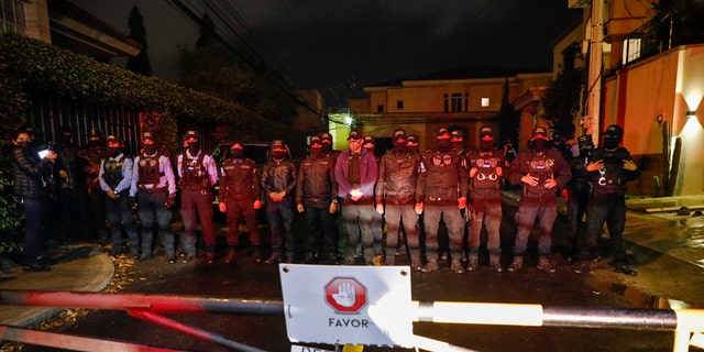 Special Forces Police block a street near the house of former Honduran President Juan Orlando Hernandez, behind a residential sign that reads in Spanish "Please, check in with security," in Tegucigalpa, Honduras, late Monday, Feb. 14, 2022. 