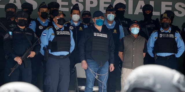 Former Honduran President Juan Orlando Hernandez, center in chains, is shown to the press at the Police Headquarters in Tegucigalpa, Honduras, Tuesday, Feb. 15, 2022. 