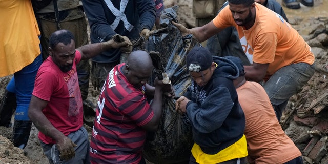 Residents and volunteers remove the body of a mudslide victim in Petropolis, Brazil, Wednesday, Feb. 16, 2022. 