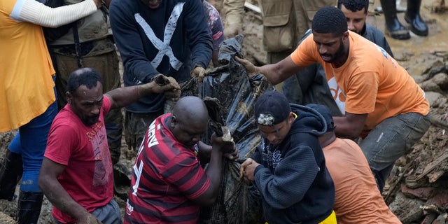 Residents and volunteers remove the body of a mudslide victim in Petropolis, Brazil, Wednesday, Feb. 16, 2022.