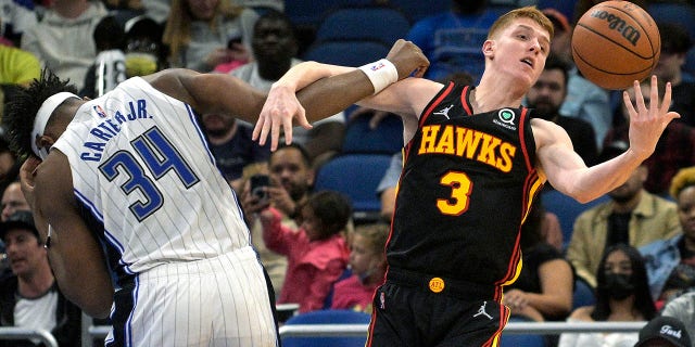 Atlanta Hawks guard Kevin Huerter (3) grabs a rebound next to Orlando Magic center Wendell Carter Jr. (34) during the first half of an NBA basketball game Wednesday, 2月. 16, 2022, in Orlando, フラ.