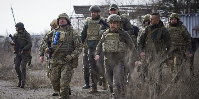 Ukrainian President Volodymyr Zelenskyy, center, pays a visit to the front line in the Donetsk region, eastern Ukraine, on Feb. 24, 2022.