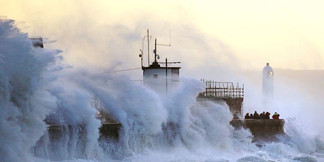 Waves crash against the sea wall and Porthcawl Lighthouse in Porthcawl, Bridgend, Wales, Britain, as Storm Eunice makes landfall Friday, Feb. 18, 2022.