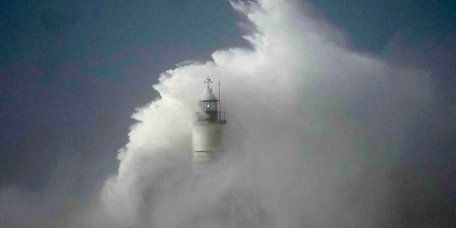 Waves crash over the Newhaven harbour breakwater and lighthouse, as Storm Eunice hits Newhaven, on the south coast of England, Friday, Feb. 18, 2022.