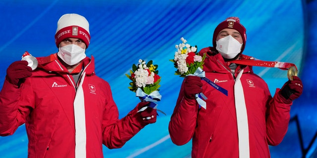 Silver medalist Switzerland's Alex Fiva, left, and Gold medalist Switzerland's Ryan Regez pose during a medal ceremony for the freestyle skiing men's cross competition at the 2022 Winter Olympics, Friday, Feb. 18, 2022, in Zhangjiakou, China.