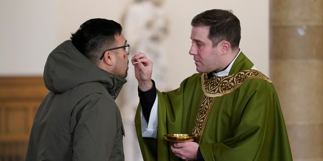 Father Matthew Hood distributes Holy Communion at Our Lady of the Rosary church Friday, Feb. 18, 2022, in Detroit. (AP Photo/Paul Sancya)