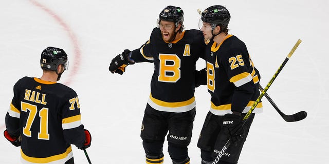 Boston Bruins' David Pastrnak is congratulated by Brandon Carlo (25) and Taylor Hall after scoring against the Colorado Avalanche during the second period of an NHL hockey game Monday, Feb. 21, 2022, in Boston.