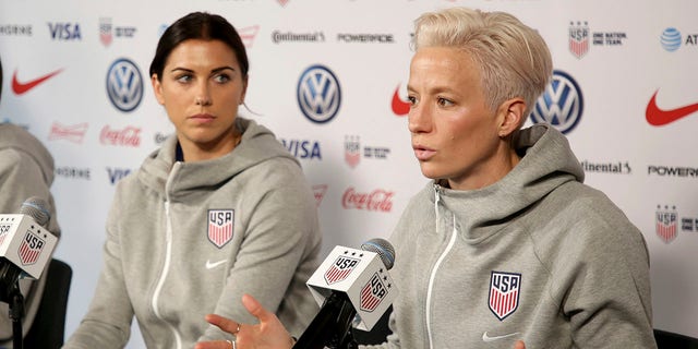 FILE - United States women's national soccer team members Alex Morgan, left, listens as teammate Megan Rapinoe speak to reporters during a news conference in New York, Friday, May 24, 2019. U.S. women soccer players reached a landmark agreement with the sport’s American governing body to end a six-year legal battle over equal pay, a deal in which they are promised $24 million plus bonuses that match those of the men. The U.S. Soccer Federation and the women announced a deal Tuesday, Feb. 22, 2022, that will have players split $22 million, about one-third of what they had sought in damages.