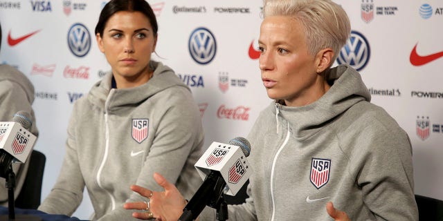 FILE - United States women's national soccer team members Alex Morgan, left, listens as teammate Megan Rapinoe speak to reporters during a news conference in New York, Friday, May 24, 2019. U.S. women soccer players reached a landmark agreement with the sport’s American governing body to end a six-year legal battle over equal pay, a deal in which they are promised $24 million plus bonuses that match those of the men. The U.S. Soccer Federation and the women announced a deal Tuesday, Feb. 22, 2022, that will have players split $22 million, about one-third of what they had sought in damages.
