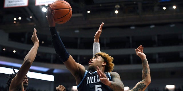 Villanova's Justin Moore shoots as Connecticut's Isaiah Whalen, left, and Tyrese Martin, back, defend during the first half of an NCAA college basketball game Tuesday, Feb. 22, 2022, in Hartford, Conn.