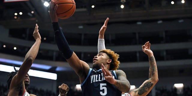 Villanova's Justin Moore shoots as Connecticut's Isaiah Whalen, left, and Tyrese Martin, back, defend during the first half of an NCAA college basketball game Tuesday, Feb. 22, 2022, in Hartford, Conn.