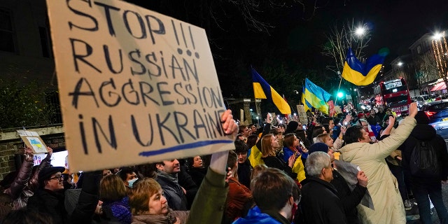 Demonstrators hold placards and flags as they attend a protest outside the Russian Embassy, in London, Wednesday, Feb. 23, 2022. Ukraine urged its citizens to leave Russia as Europe braced for further confrontation Wednesday after Russia's leader received authorization to use military force outside his country and the West responded with a raft of sanctions.