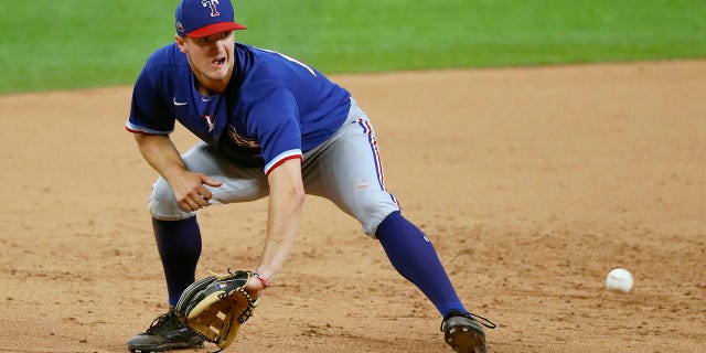 FILE - Texas Rangers infielder Josh Jung reaches down to field a ground ball in an intrasquad game during baseball practice at Globe Life Field in Arlington, Texas, Friday, July 10, 2020. Texas Rangers top prospect Josh Jung had surgery Wednesday, Feb. 23, 2022 to repair a torn labrum in his left shoulder, ending the third baseman's chance of being an option for the big league roster this spring.