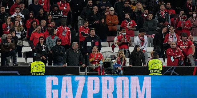 An advertisement for the Russian state-owned gas company Gazprom displayed on an advertising board as Benfica fans attend the second half of the Champions League round of 16, first leg, soccer match between Benfica and Ajax at the Luz stadium in Lisbon, Wednesday, Feb. 23, 2022.
