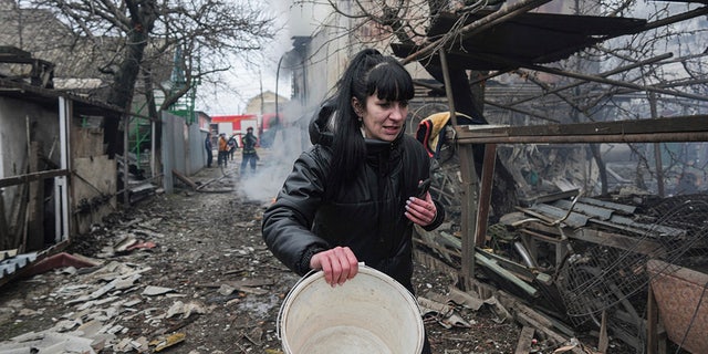 A woman walks past the debris in the aftermath of Russian shelling, in Mariupol, Ukraine (AP Photo/Evgeniy Maloletka)