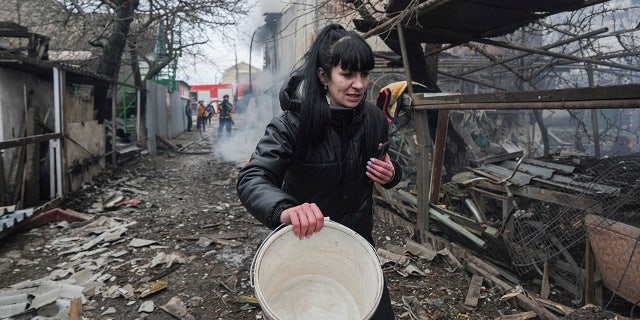 A woman walks past the debris in the aftermath of Russian shelling, in Mariupol, Ukraine, Thursday, Feb. 24, 2022.