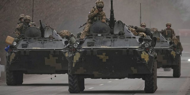 Ukrainian servicemen sit atop armored personnel carriers driving on a road in the Donetsk region, eastern Ukraine, Thursday, Feb. 24, 2022. 