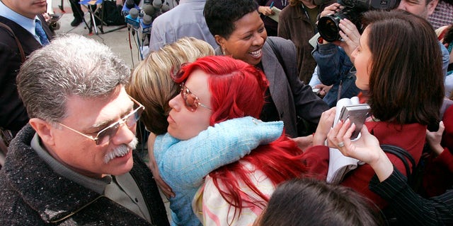 Juror Richelle Nice, center, hugs attorney Gloria Allred after speaking at a news conference after the formal sentencing of Scott Peterson in Redwood City, California, on March 16, 2005.