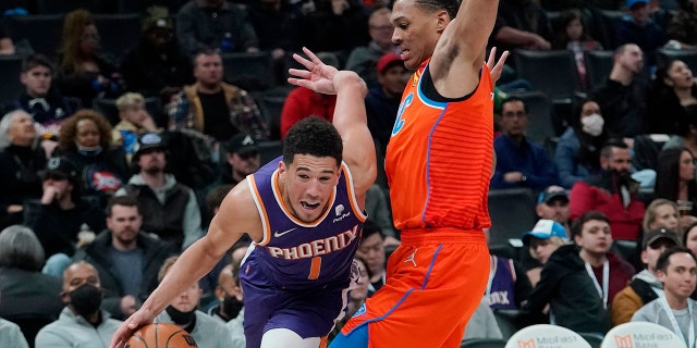 Phoenix Suns guard Devin Booker (1) drives around Oklahoma City Thunder forward Darius Bazley (7) in the second half of an NBA basketball game Thursday, Feb. 24, 2022, in Oklahoma City.