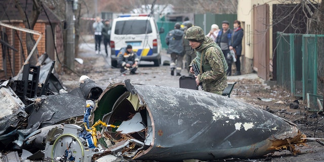 A Ukrainian Army soldier inspects fragments of a downed aircraft in Kyiv, Ukraine, on Friday, Feb. 25, 2022. It was unclear what aircraft crashed and what brought it down. Russia is pressing its invasion of Ukraine to the capital's outskirts after unleashing airstrikes on cities and military bases and sending in troops and tanks. 