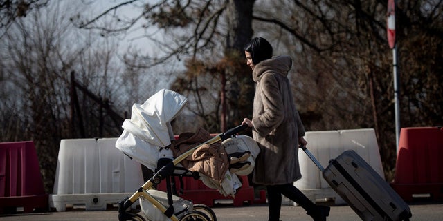 A woman pushes a baby stroller after crossing the border from Ukraine at the Romanian-Ukrainian border, in Siret, Romania, on Friday, Feb. 25, 2022. Thousands of Ukrainians are fleeing from war by crossing their borders to the west in search of safety. They left their country as Russia pounded their capital and other cities with airstrikes for a second day on Friday. 