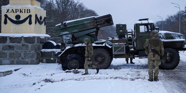 Ukrainian service members walk by a deactivated Russian military multiple rocket launcher on the outskirts of Kharkiv, Ukraine, Friday, Feb. 25, 2022.