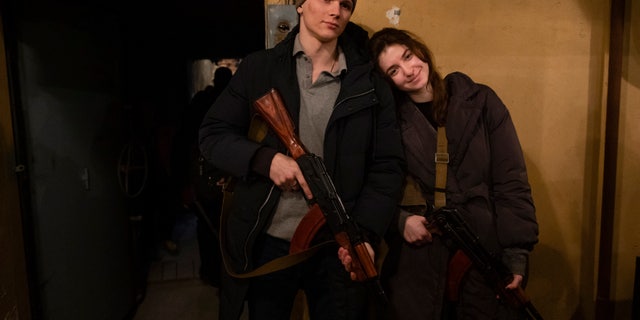 Newly married couple Yarina Arieva and Svyatoslav Fursinb pose for a photo after they joined the ranks of the city territorial defense the day after they got married in Kyiv, Ukraine, on Friday, Feb. 25, 2022.