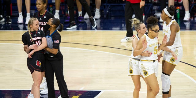 An official holds Louisville's Hailey Van Lith (10) while Notre Dame's Dara Mabrey holds teammate Olivia Miles (5), next to Maya Dodson (0) after an altercation on the court during the first half of an NCAA college basketball game Sunday, Feb. 27, 2022, in South Bend, Ind.