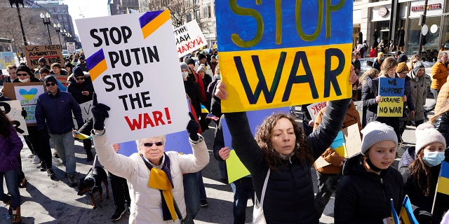 Demonstrators display placards as they march during a rally in support of Ukraine, Sunday, Feb. 27, 2022, in Boston.