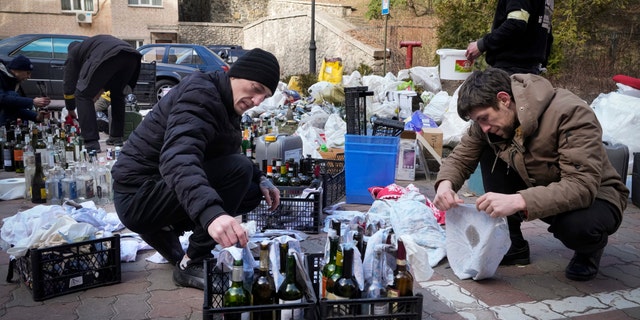 Members of civil defense prepare Molotov cocktails in a yard in Kyiv, Ukraine, Sunday, Feb. 27, 2022. (AP Photo/Efrem Lukatsky)