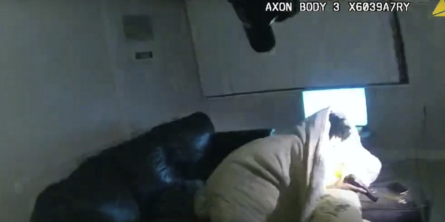 A Minneapolis police body camera image shows 22-year-old Amir Locke wrapped in a blanket on a couch, holding a gun, moments before he was fatally shot by police as they were executing a search warrant in a homicide investigation.