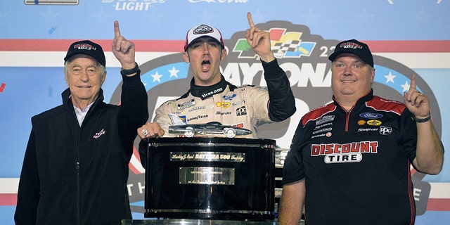 Austin Cindric, center, celebrates in Victory Lane with car owner Roger Penske, left, and crew chief Jeremy Bullins after winning the NASCAR Daytona 500 auto race at Daytona International Speedway, Sunday, Feb. 20, 2022, in Daytona Beach, Florida.